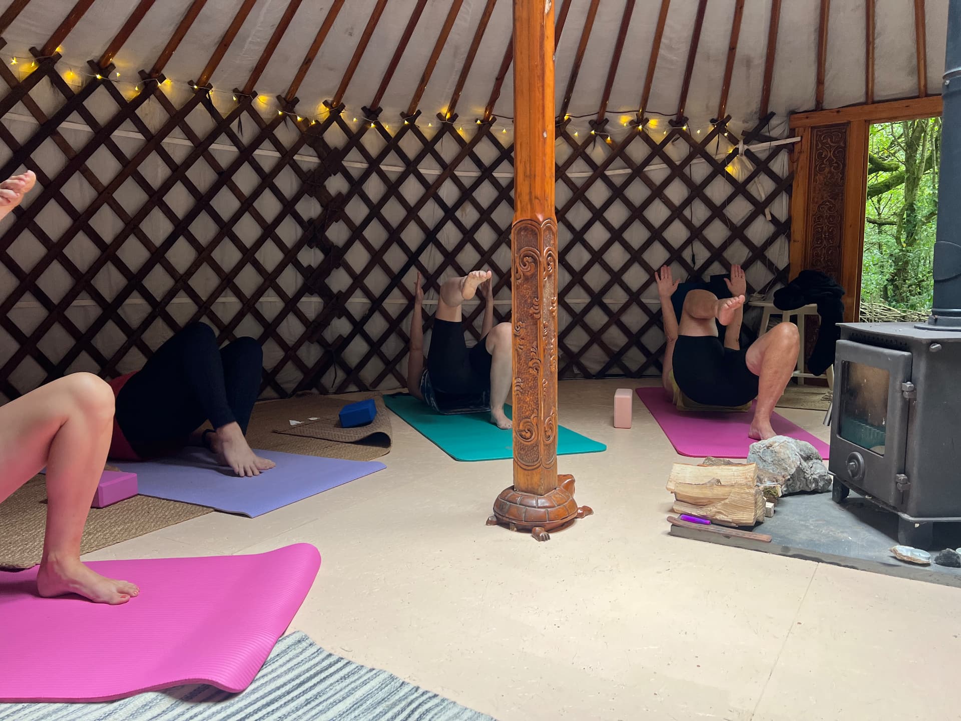 Retreat guests practising Pilates on mats inside the candlelit yurt