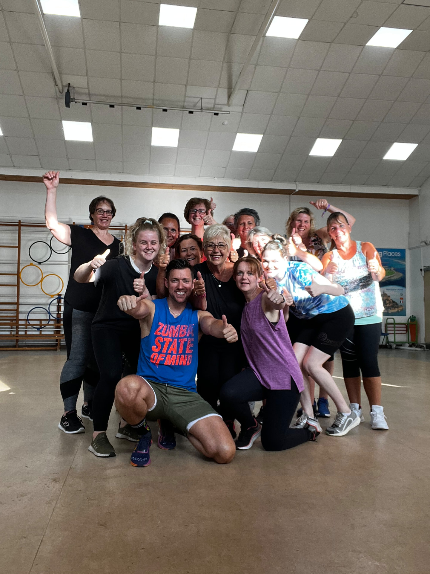 Jason kneeling with a Zumba class giving thumbs up