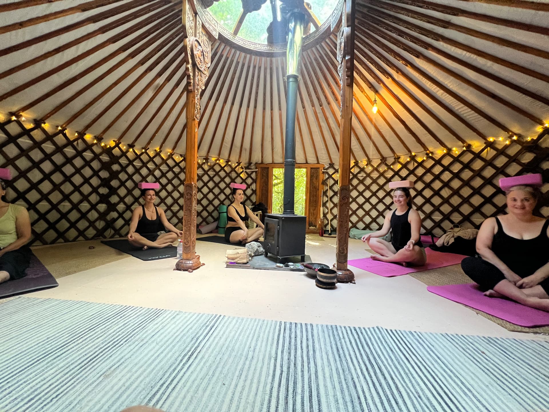 Wide view of the yurt with retreat guests balancing blocks around the wood burner