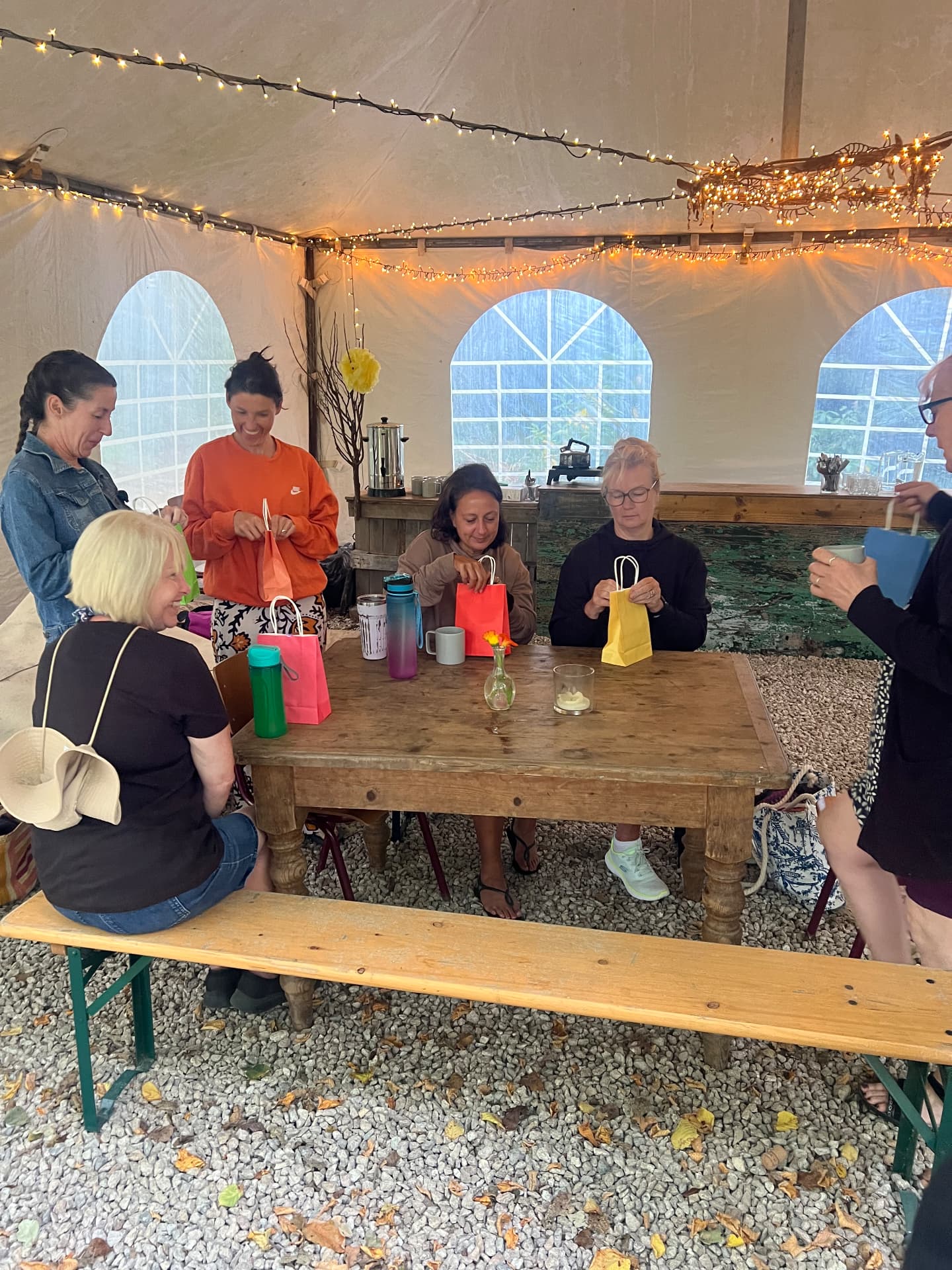 Retreat guests chatting over tea around the wooden table in the marquee