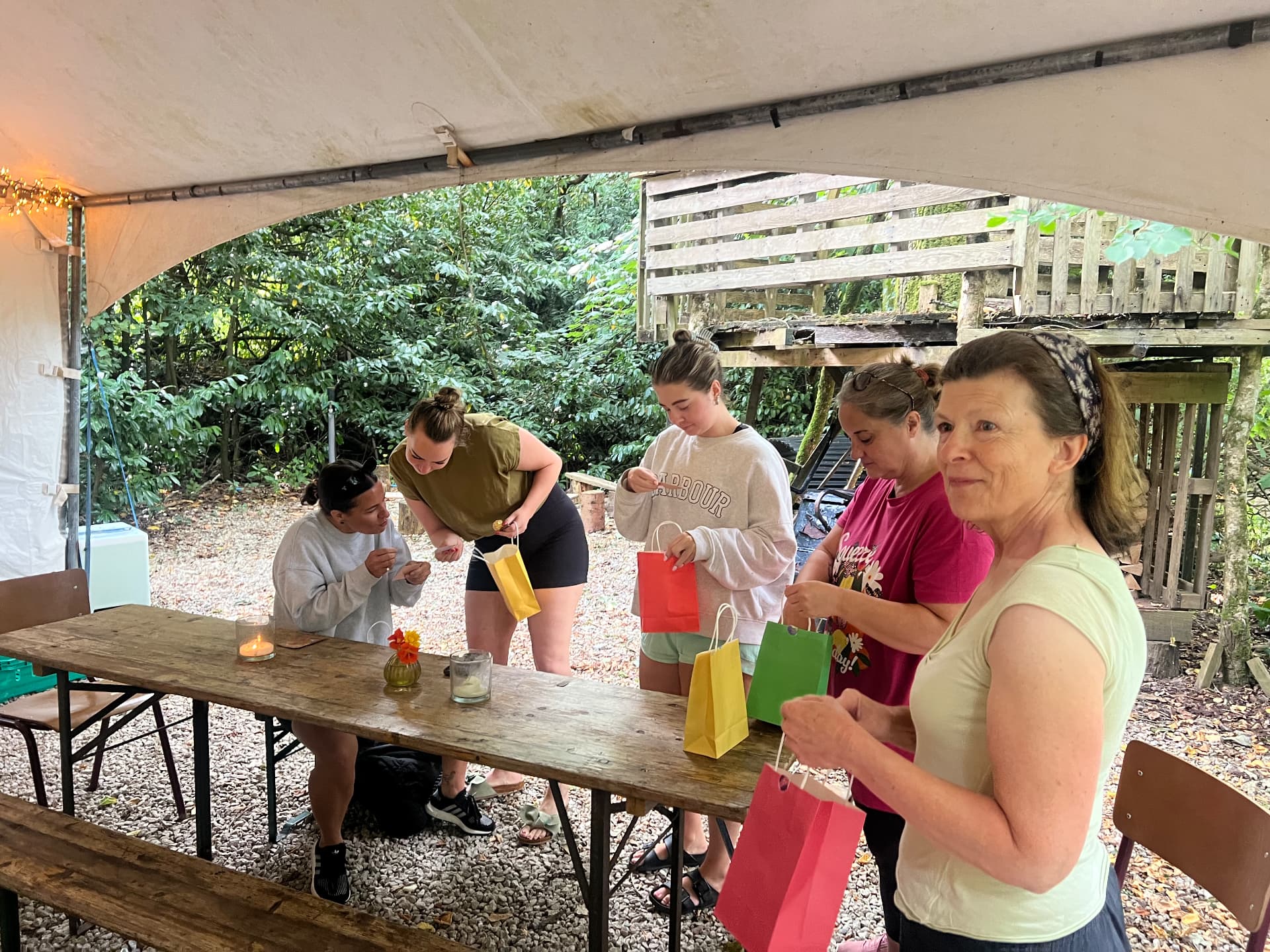 Retreat guests opening gift bags under the canopy in the woods