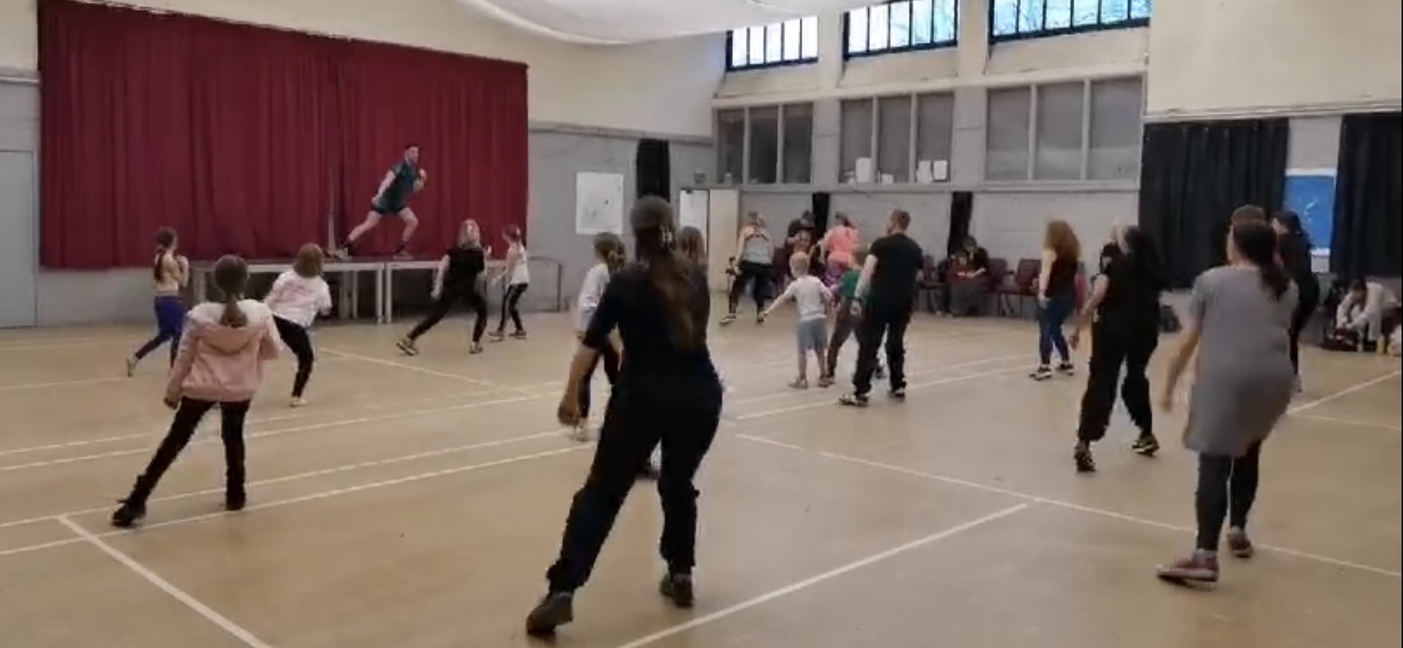 Busy community dance class mid-routine as Jason leads from the stage