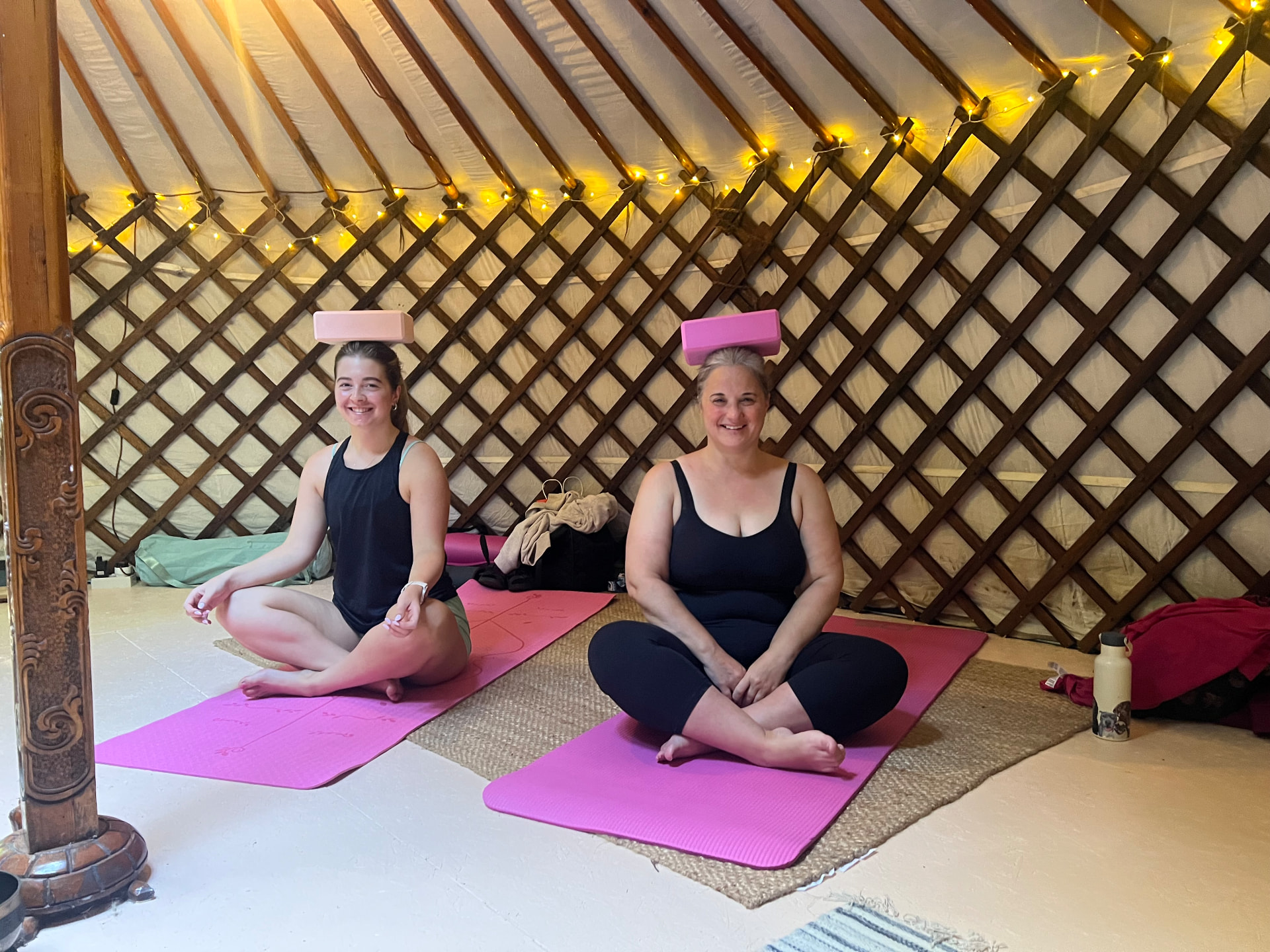 Guests seated in meditation inside the retreat yurt, candlelight and woodburner