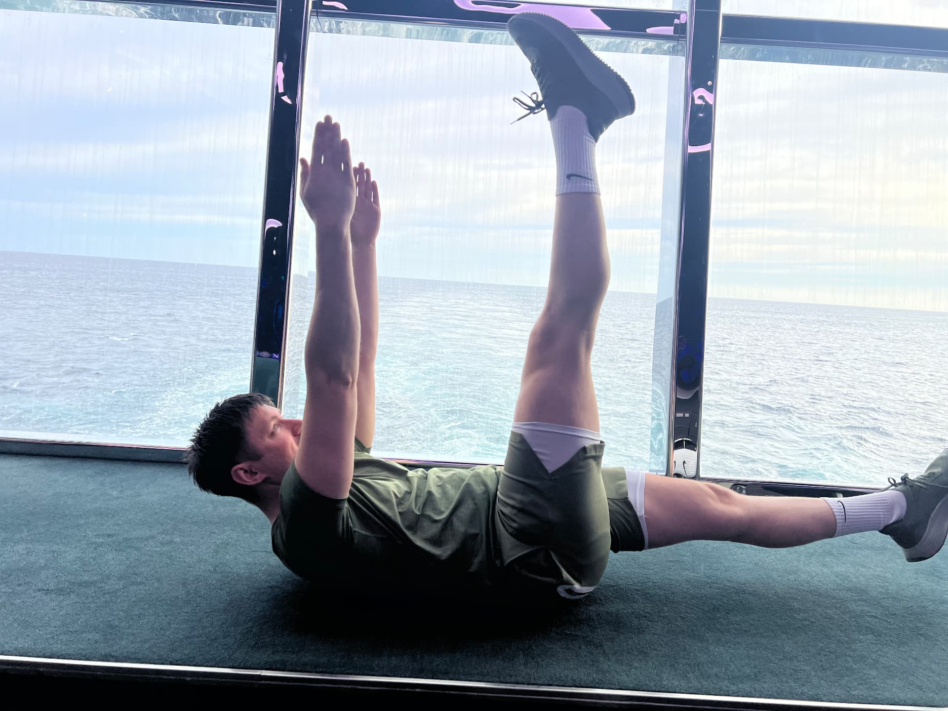 Jason performing the Pilates hundred beside panoramic ocean windows