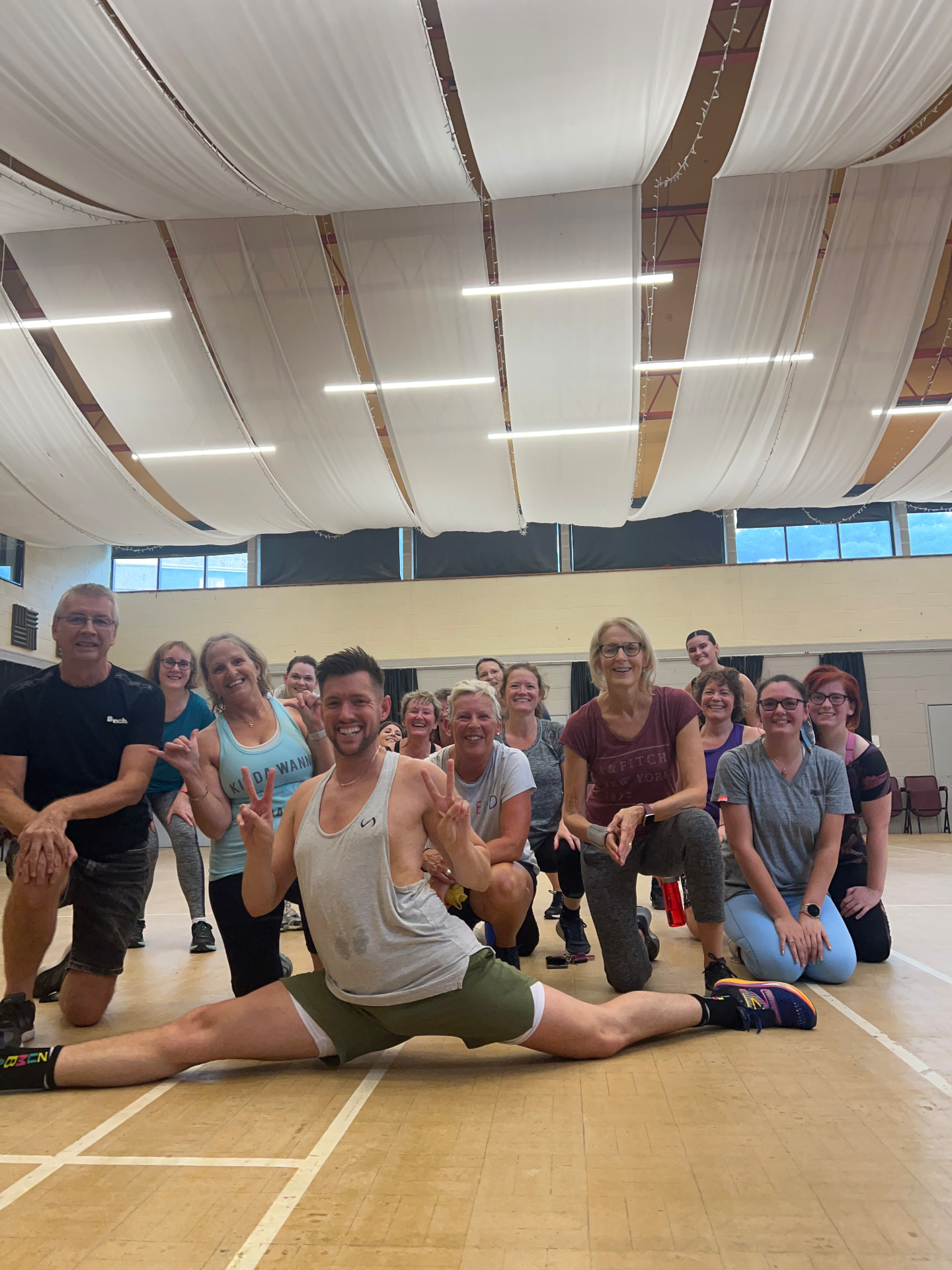 Jason holding the splits on the floor surrounded by his smiling class