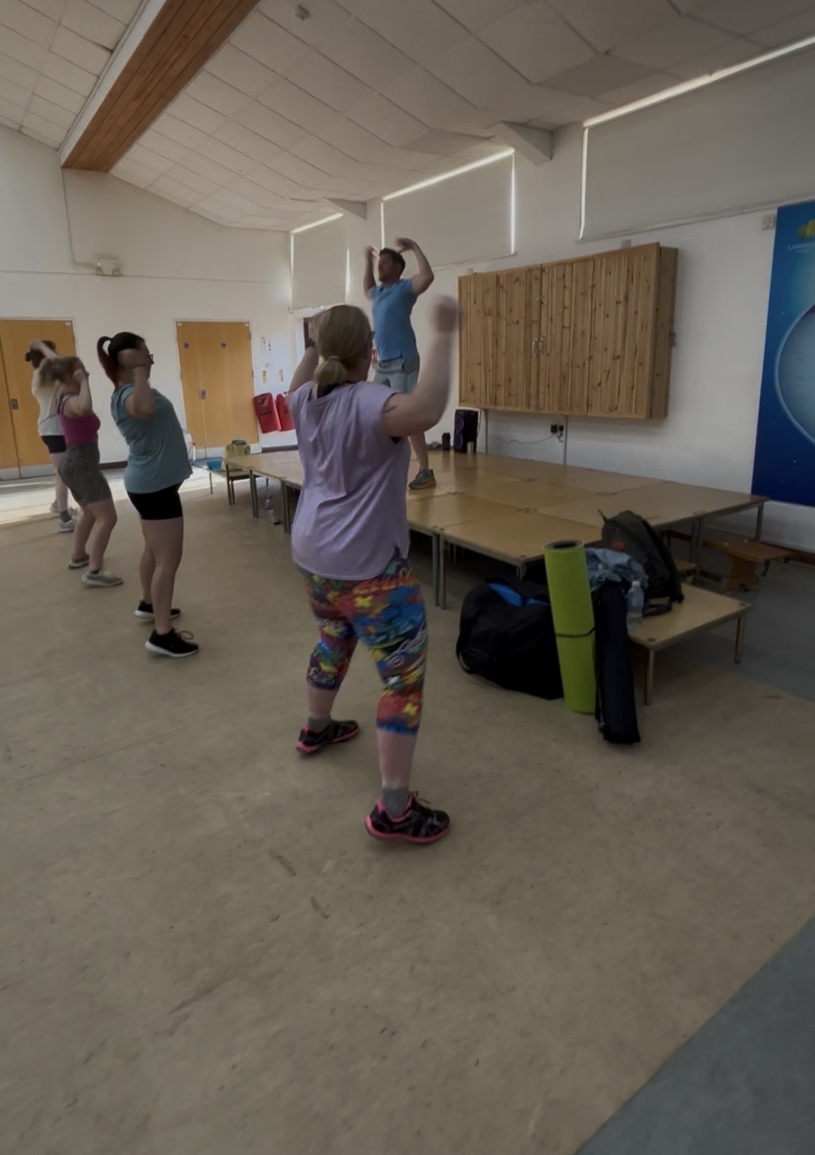 Jason leading a dance routine with his class in a village hall