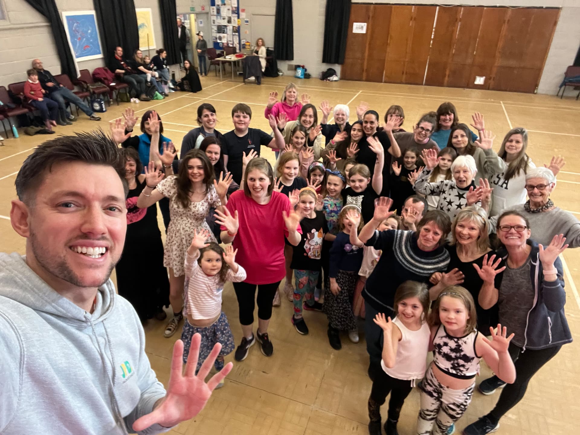 Jason and a hall full of class members waving after a Zumba session