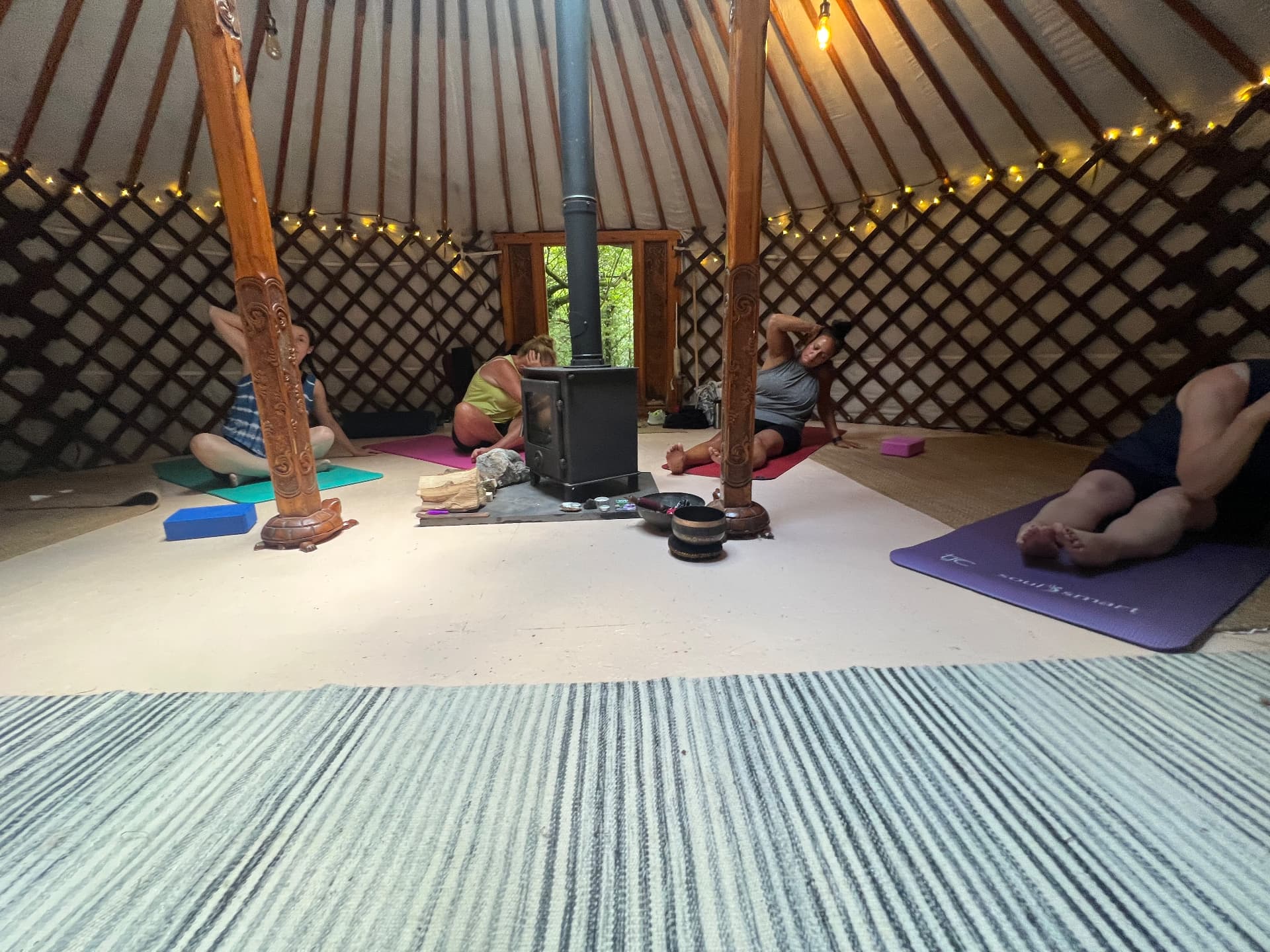 Retreat guests stretching on mats inside the fairy-lit yurt