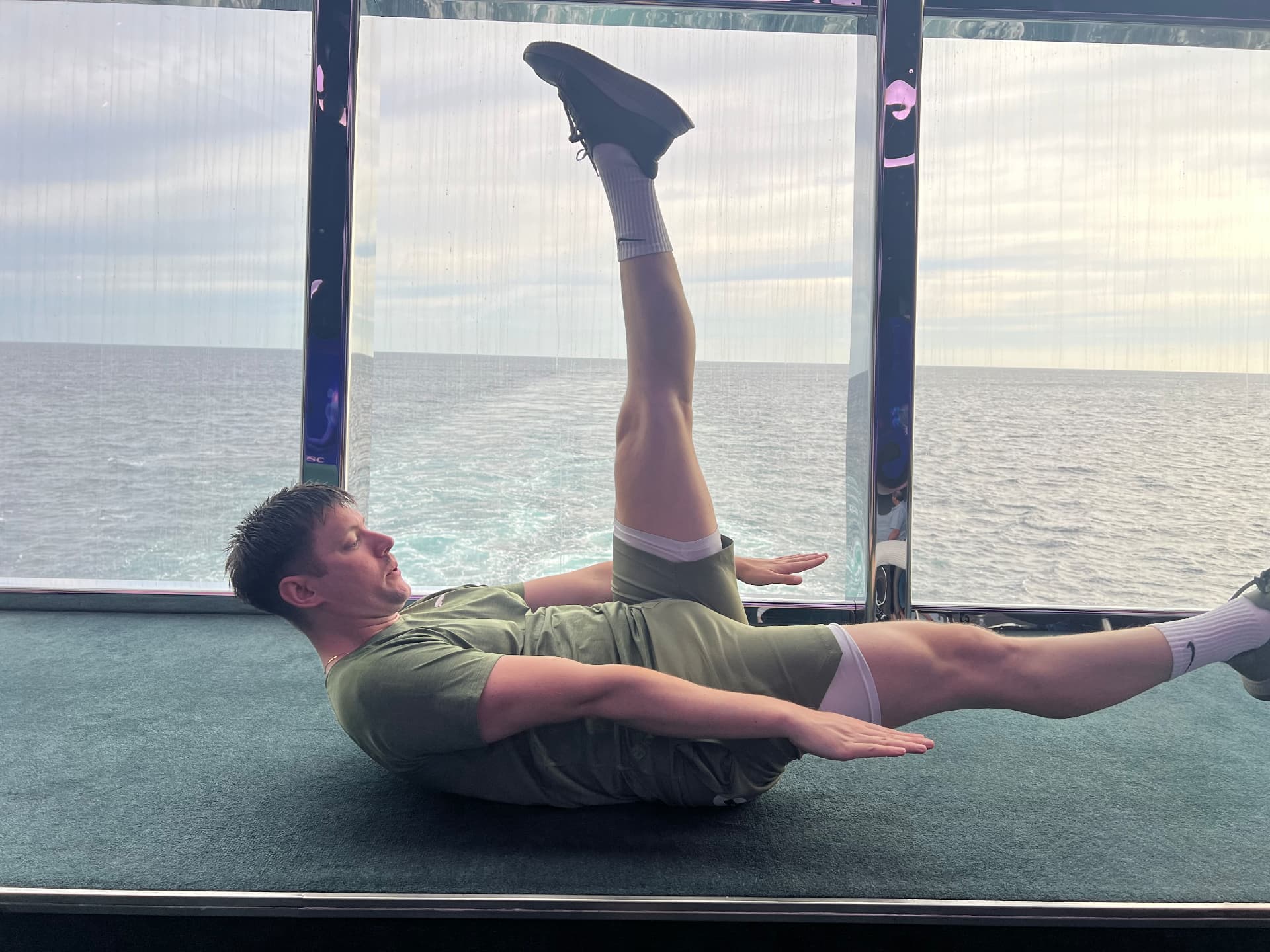 Jason performing a single leg Pilates teaser with the sea behind him