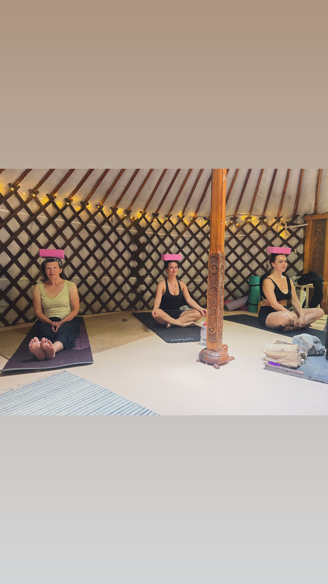 Three retreat guests seated on mats in the yurt balancing blocks